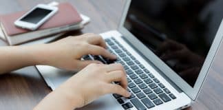 Closeup of business woman hand typing on laptop keyboard