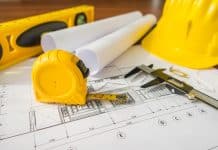 Construction plans with yellow helmet and drawing tools on bluep