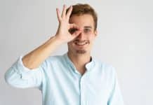 Joyful smiling handsome guy imitating binoculars