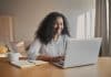 Cheerful young African American woman copywriter sitting in fron