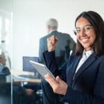 Happy female professional in glasses and suit holding tablet