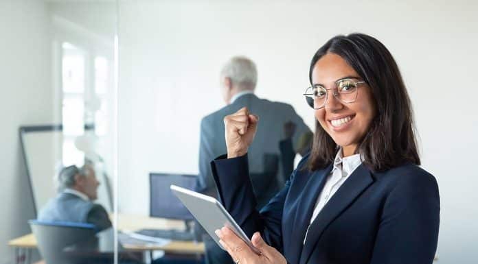 Happy female professional in glasses and suit holding tablet