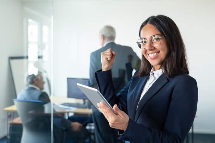 Happy female professional in glasses and suit holding tablet